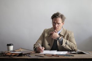 Serious businessman taking notes in documents during coffee break in office