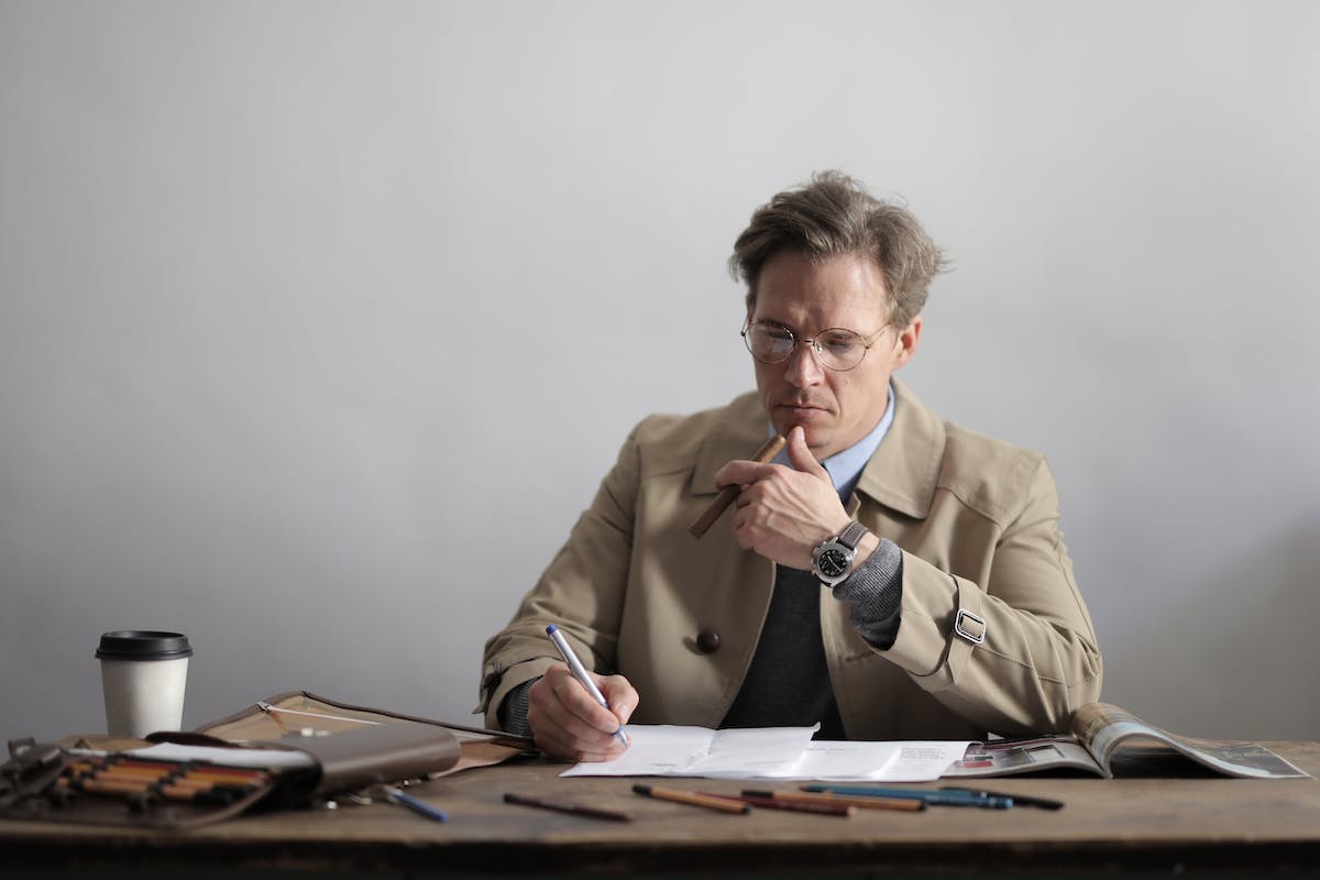 Serious businessman taking notes in documents during coffee break in office